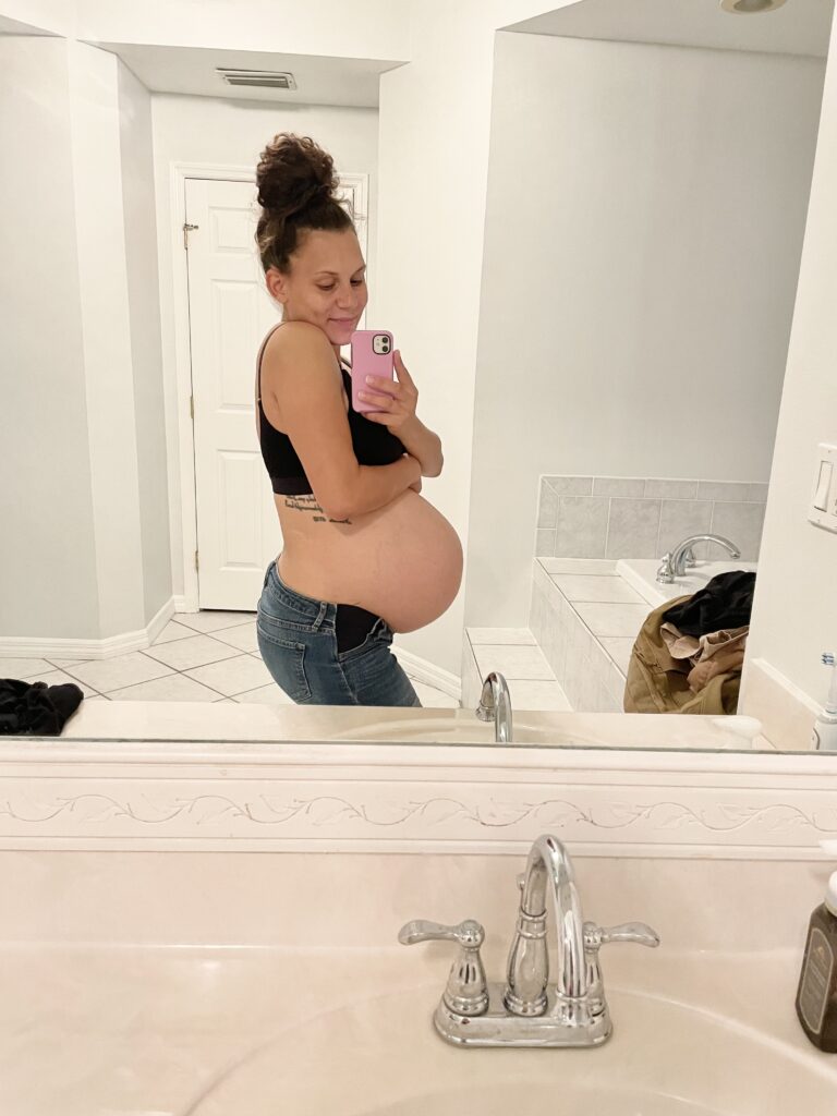 Picture of pregnant woman smiling while taking a picture in the mirror 