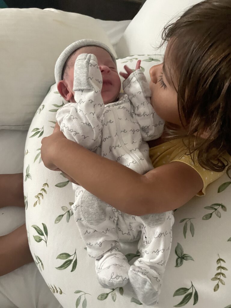 Picture of little girl holding a newborn baby on a pillow